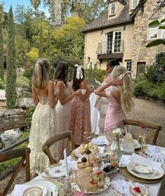 a group of women standing around a table with plates and cups on top of it