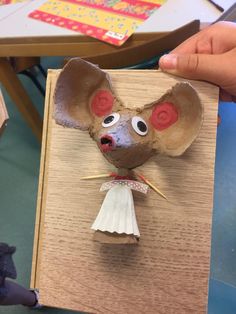 a paper mouse with red eyes on it's head is being held up by someone