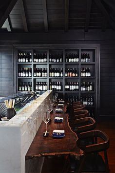 a long wooden table sitting in front of a wine rack filled with bottles and glasses