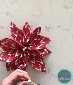 someone is making a paper poinsettia decoration