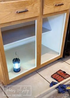 a light shines in between two glass doors on a wooden cabinet that is being built