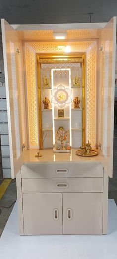 a white cabinet sitting inside of a room next to a mirror and shelf with gold decorations on it