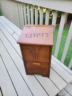 a wooden box with the word taters written on it sitting on a white porch