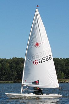 a person on a sailboat in the water with trees in the backgroud