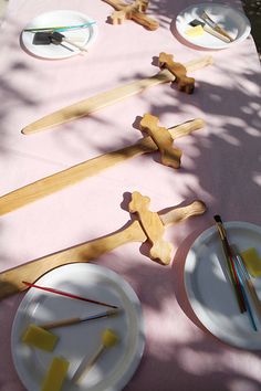 the table is set up with wooden crosses, plates and utensils on it