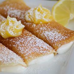 lemon filled crepes with powdered sugar on top and garnished with lemon wedges