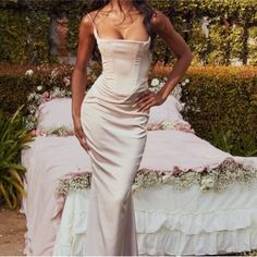 a woman in a white dress standing next to a bed with flowers on the headboard