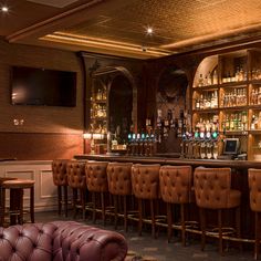 a dimly lit bar with leather chairs and shelves