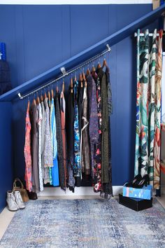 a room with blue walls and lots of clothes hanging on the rack in front of it