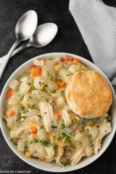 a bowl filled with chicken pot pie soup next to two spoons and a napkin