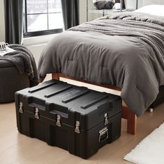 a bedroom with a bed and two storage boxes on the floor in front of it