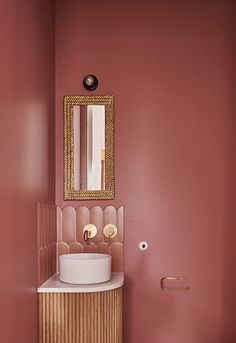 a bathroom with pink walls and gold accents