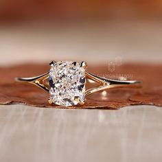 a close up of a diamond ring on top of a wooden surface with leaves around it