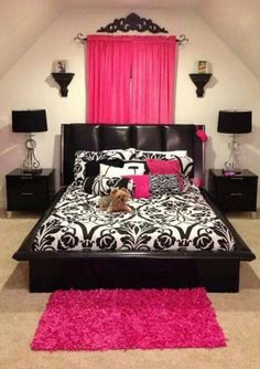 a black and white bed with pink rugs on the floor next to two nightstands