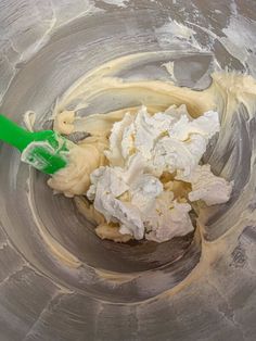 a mixing bowl filled with white batter and green spatula for icing in it