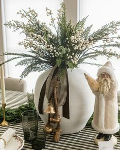 a table topped with a vase filled with flowers and gnome figurines next to a window