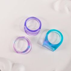 three different colored plastic rings on a white surface