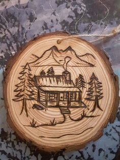 a piece of wood with a drawing of a cabin in the woods on it's side