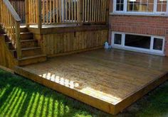 a wooden deck in front of a brick house