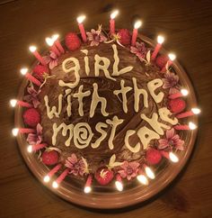 a birthday cake with lit candles and the words girl with the most car written on it