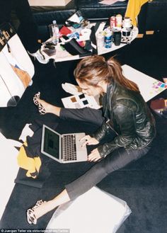 a woman is sitting on the floor with her laptop and other office supplies in front of her