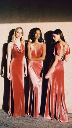 three women standing next to each other in long dresses