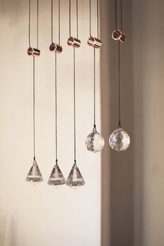 four hanging glass ornaments in various shapes and sizes, suspended from the ceiling by copper fittings