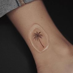 a small palm tree tattoo on the left inner forearm and wrist, is shown in this image