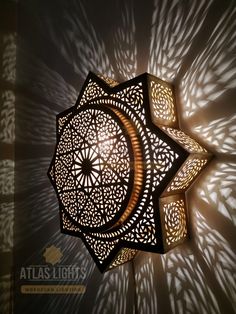 an intricately designed light fixture is shown on the wall with shadows from its lampshade