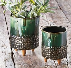 two green planters sitting on top of a wooden table next to each other with plants in them