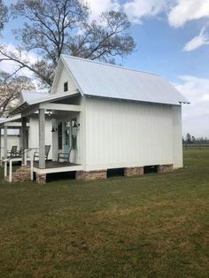 a small white house sitting on top of a lush green field