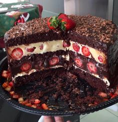 a large chocolate cake with strawberries on top is cut in half to show the layers