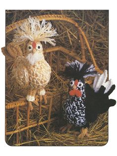 two knitted chickens sitting on top of hay in a straw covered basket with one chicken standing next to the other