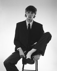 a man in a suit and tie sitting on a stool