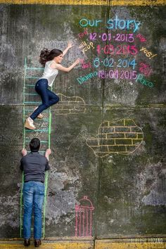 two people are drawing on the wall with chalk