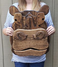 a woman holding up a wooden mask made to look like a dog's face