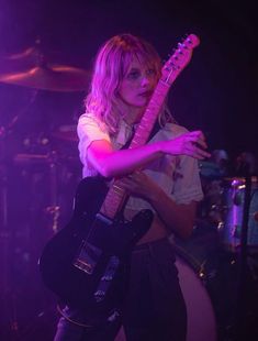 a woman holding an electric guitar in her right hand