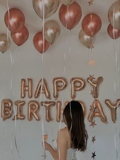 a woman standing in front of balloons that say happy birthday