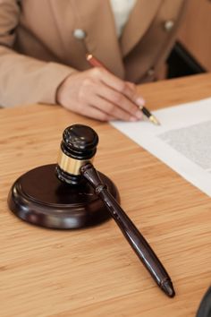 a person sitting at a table with a pen and paper in front of them, next to a judge's gaven