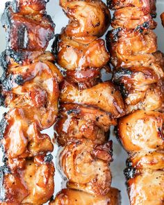 chicken skewers covered in bbq sauce on a white platter, ready to be eaten