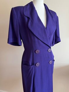 "Fabulous Tahari purple suit dress from the 1980s. Fits like a M/L (see measurements below). Coat/blazer style, crossover bodice with button front, half sleeves. Large collar, shoulder pads, pockets. Hits below-the-knee or mid-calf. Color is purple, appears like royal blue in certain light and in some photos--close-ups show most accurate color. Dress is lovely, but there are a couple of minor issues: small stain on back of dress (see next-to-last photo); small section of stitching has come loose on inside layer of fabric under the arm (see last photo), not visible on outer visible layer. Price reflects these minor flaws. Overall, the dress is in good vintage condition. Bust: 38\"+ Waist: 30\" Hips: 36\" Length: 39.5\" Sleeve Length: 11\" Label: Tahari Materials: Rayon; silk" Fitted Purple Blazer With Pockets, Formal Purple Blazer With Pockets, Fitted Double-breasted Purple Blazer, Fitted Purple Double-breasted Blazer, Formal Purple Dress With Buttons, Purple Buttoned Blazer For Office, Fitted Purple Blazer With Buttons, Purple Office Blazer With Buttons, Formal Purple Blazer With Buttons