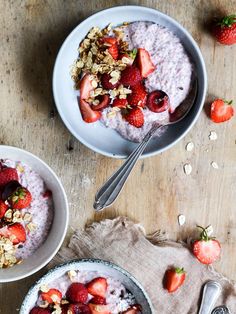 two bowls of oatmeal with strawberries and granola on the side