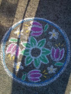 a close up view of a flower design on the ground in front of a person's shadow