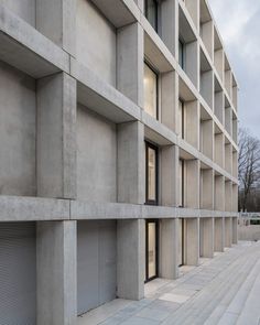 the building is made out of concrete and has several windows on each side, along with shutters