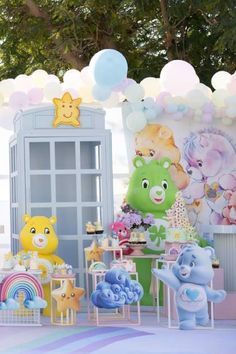 an outdoor party with balloons, decorations and stuffed animals on the table in front of a phone booth