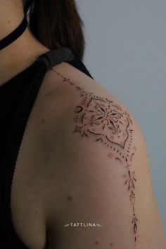 the back of a woman's shoulder with an intricate tattoo design on her arm