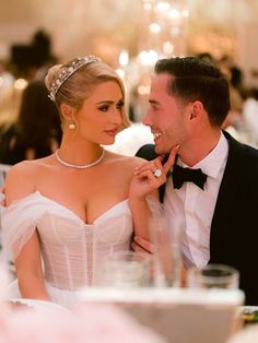 a man in a tuxedo and a woman in a wedding dress sitting at a table