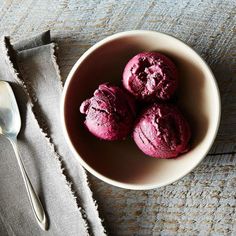 three scoops of ice cream sit in a bowl next to a spoon and napkin