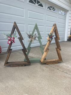 three wooden christmas trees sitting in front of a garage