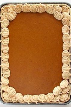 a square shaped cake in a pan with icing on the top and some cookies around it